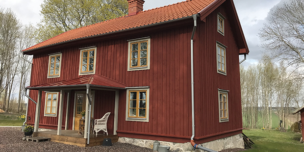 Det hus som Henrik Carlsson har renoverat. Det är i två våningar. Faluröd panel på fasaden. Ockragula fönster och grå fönsterfoder. 