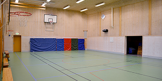 Bänkar, basketkorgar och gymnastikmattor i Ekeby gymnastiksal.