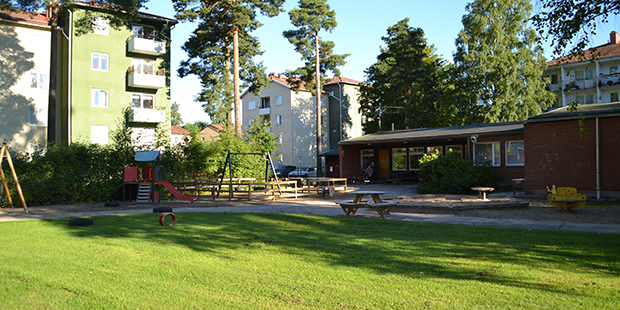 Bilden visar Björnens förskola. Ett hus med svart fasad och grönt gräs.
